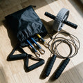 Pack complet Amplitude sur un parquet : le kit 11 pièces dans son sac avec ses tubes et ses poignées, la roue abdominale et la corde à sauter