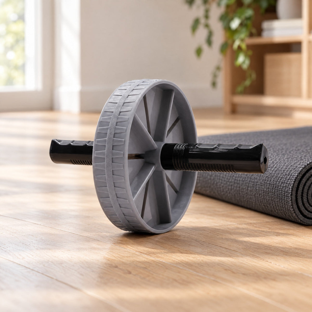 Roue abdominale posée sur un parquet clair à côté d'un tapis enroulé